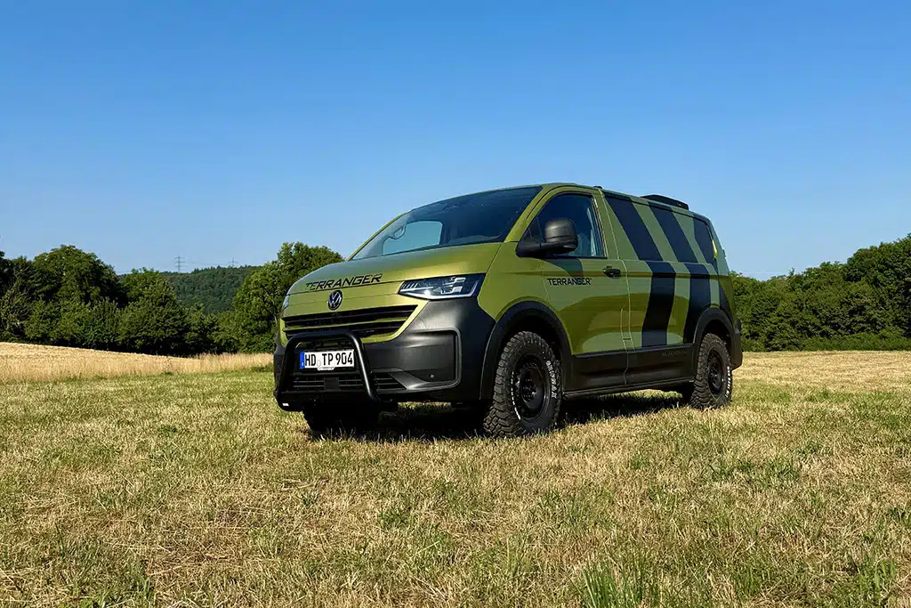 Ein Allrad-Ford-Tourneo-Custom grün foliert mit schwarzen Streifen und Terranger-Schriftzug steht auf einer Wiese.