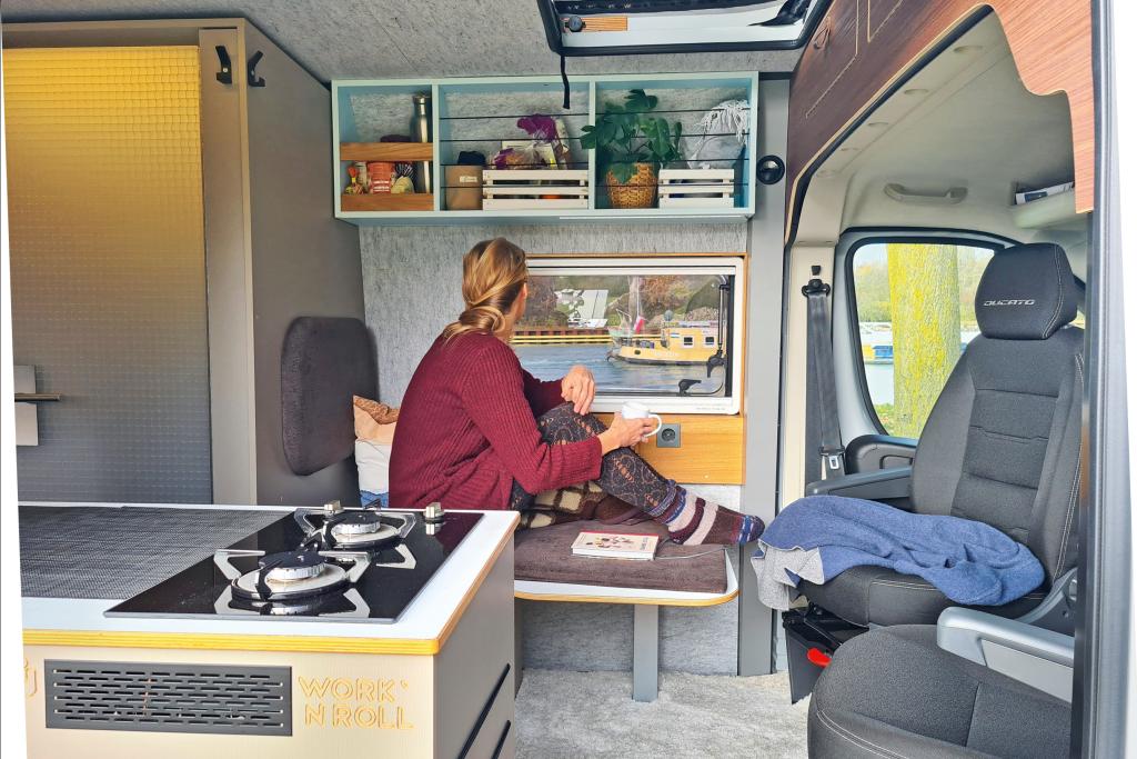 Frau sitzt auf Lungeartigem Sitz im Campervan