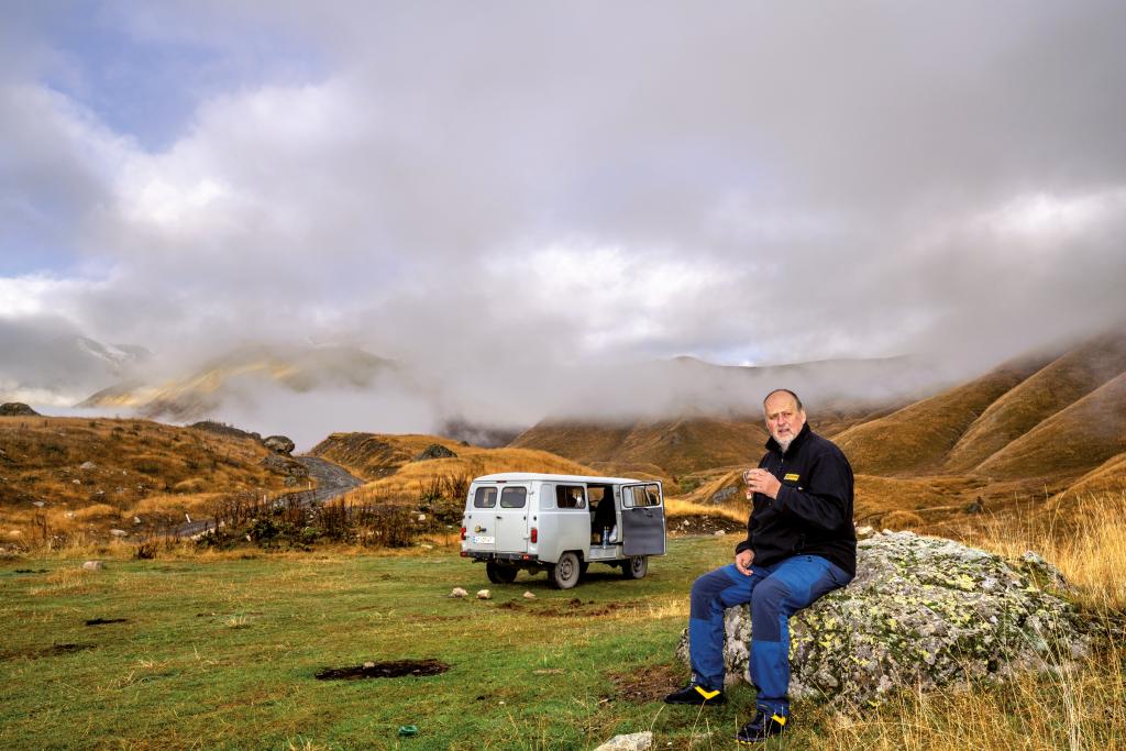 Mann mit Campervan im Hintergrund in georgischer Landschaft