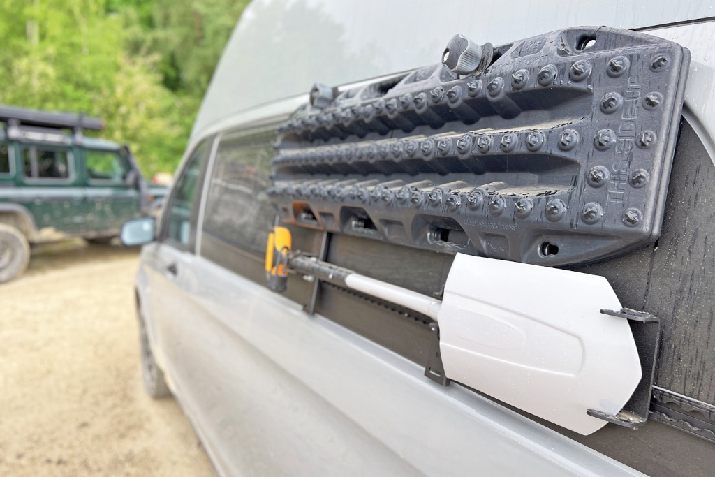 An der Fahrerseite außen sind hinten Sandbleche und Schaufel befestigt