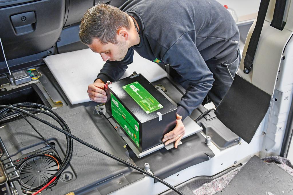 Techniker setzt eine grüne WCS-Batterie im Innenraum eines Campervans ein