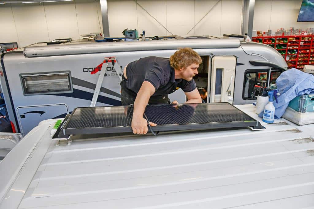 Techniker montiert ein Solarmodul auf dem Dach eines Campervans
