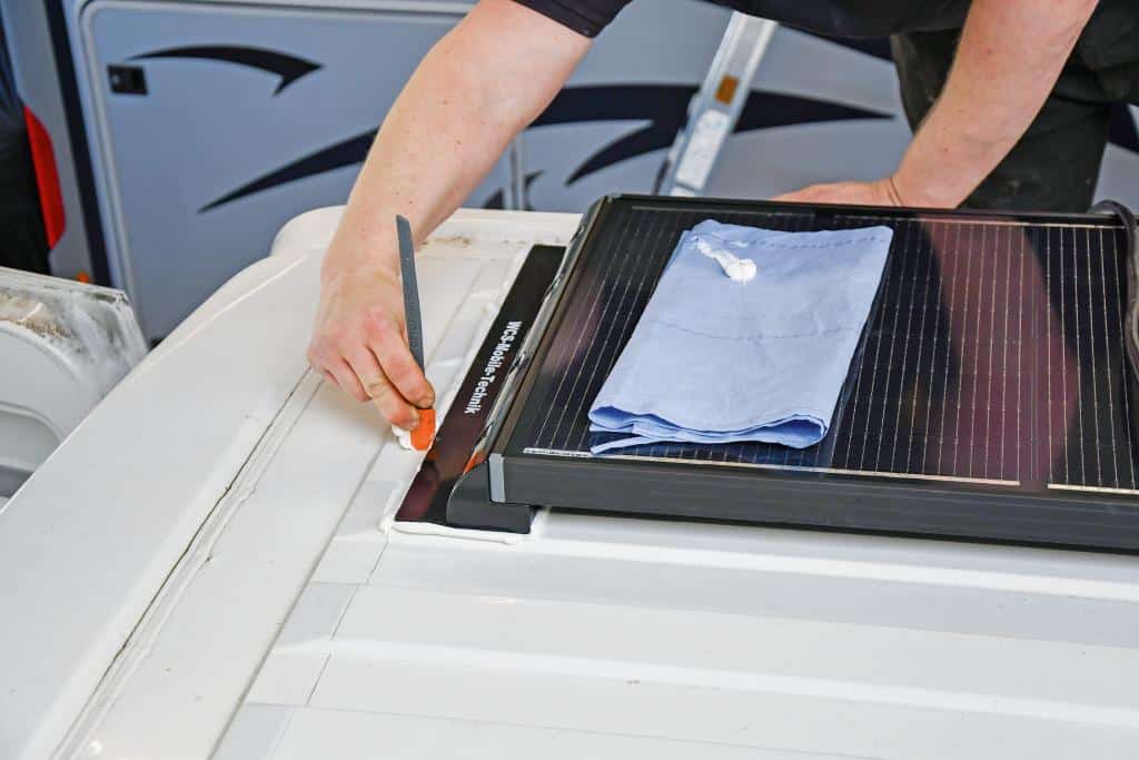 Hand bearbeitet die Befestigung eines Solarmoduls auf dem Dach eines Fahrzeugs