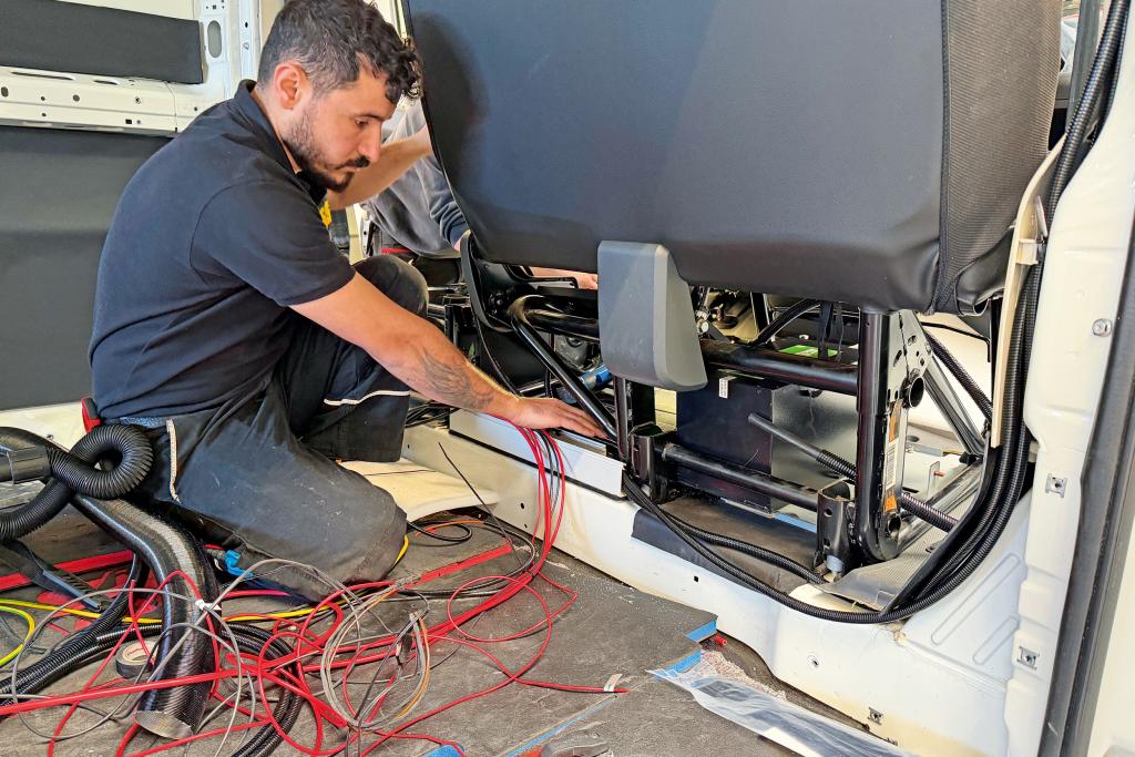 Techniker verlegt rote Kabel im Innenraum eines Campervans