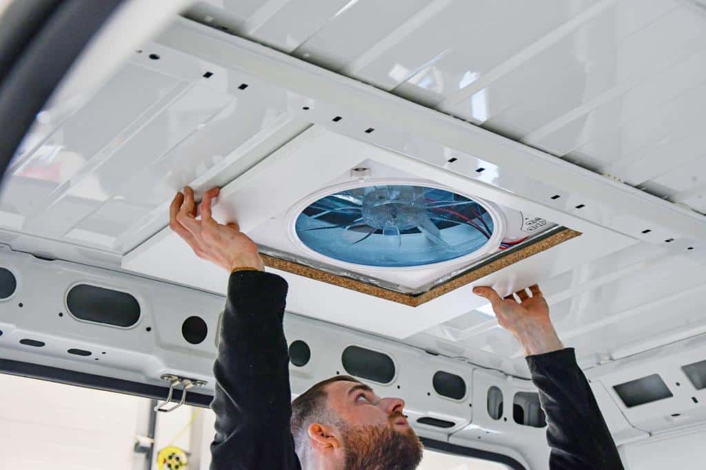 Techniker montiert einen Dachlüfter im Innenraum eines weißen Campervans