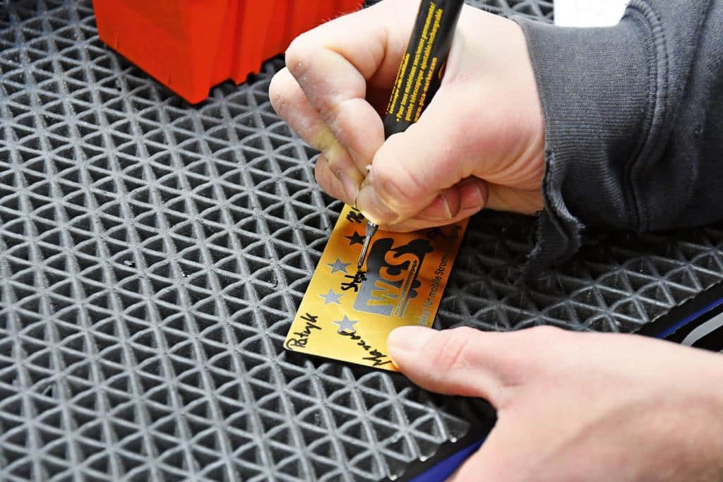 Nahaufnahme einer Hand, die eine WCS-Karte auf einer strukturierten Matte beschriftet
